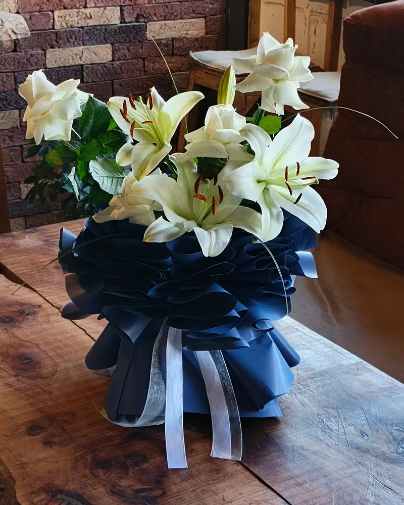 دسته گل لیلیوم سفید با بسته‌بندی سرمه‌ای