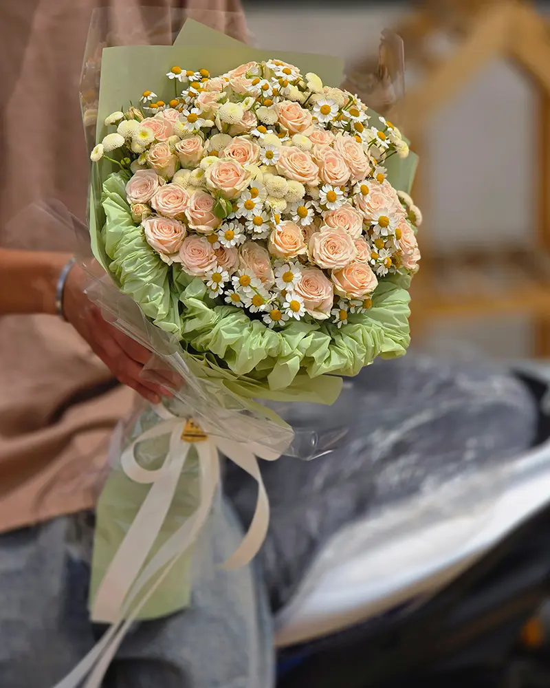 نمای نزدیک دسته گل هدیه با رز هلویی و بابونه